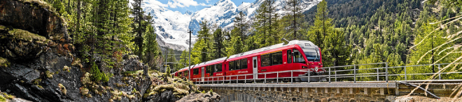 The Bernina Express crossing a bridge in the green forests of Switzerland