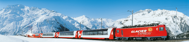 A red Glacier Express scenic train travels through the snowy Alps in Switzerland